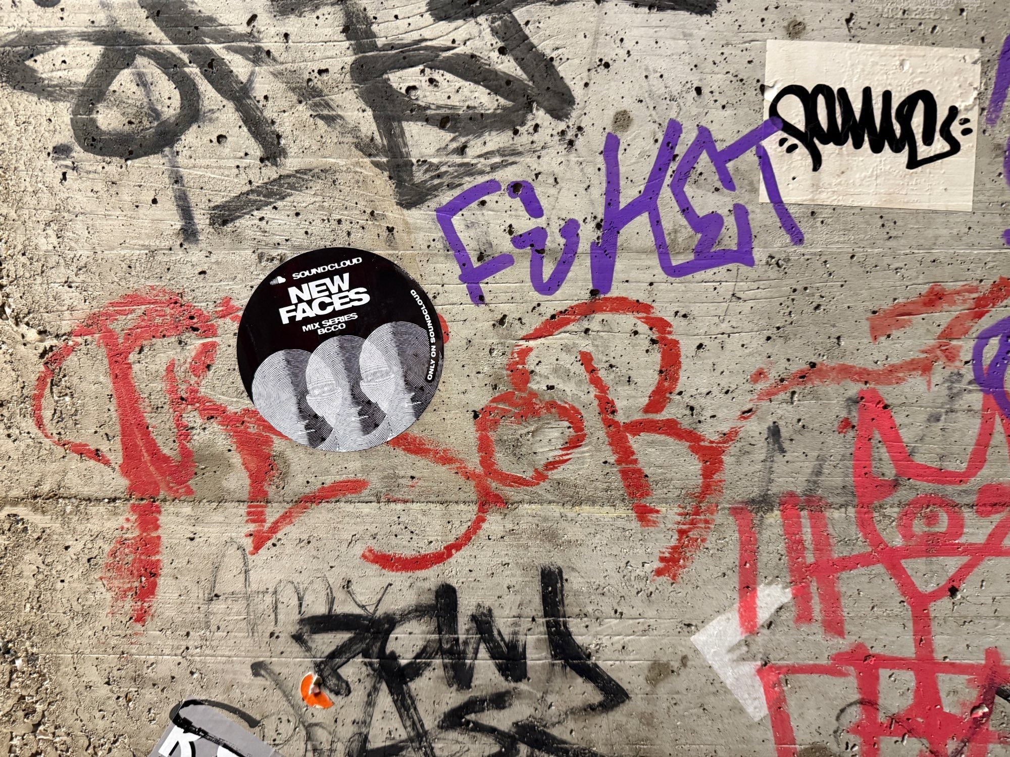 BCCO x SoundCloud New Faces Sticker on a wall of graffiti 